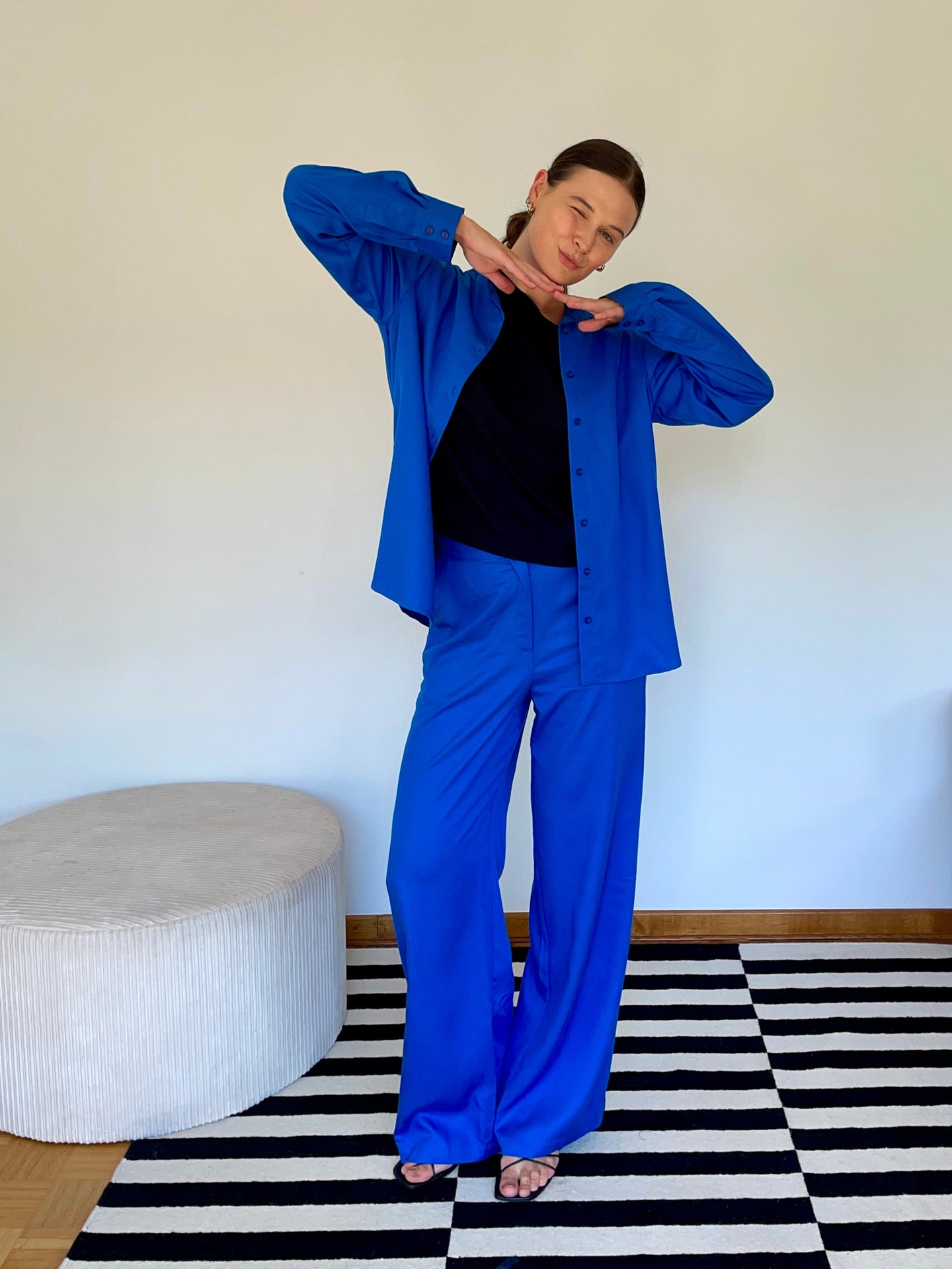 Elena wearing the Pixie  blouse & Han pants bright blue standing in a room with a black and white checkered floor.