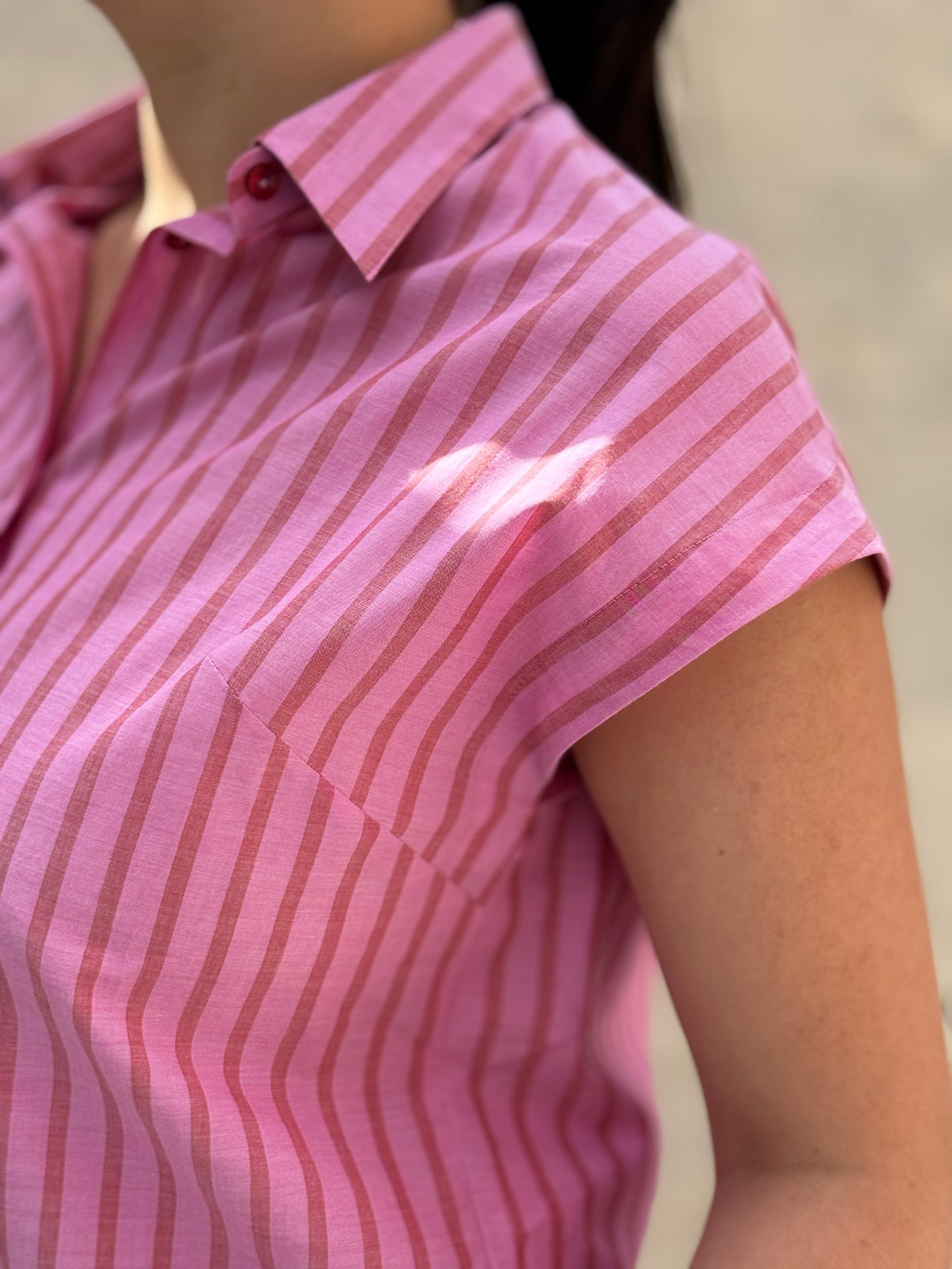 Close-up of a person wearing a pink and striped shirt.
